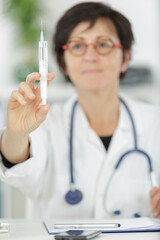 mature doctor showing hand press syringe