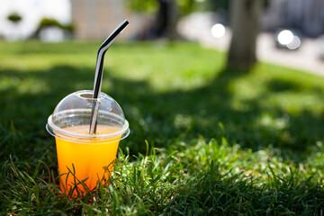 Photo of a bright cocktail on the grass. Copy space. Summer cold drink on a hot day

