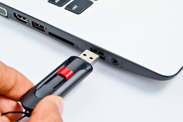 Hand inserting plug in flashdisk into usb port in laptop personal computer, data transfer device concept, close up