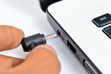 Hand holding the power plug of pc notebook isolated white background