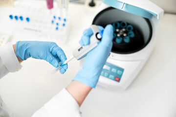 researcher using pipette and analysis flask samples into a centrifuge in laboratory.
