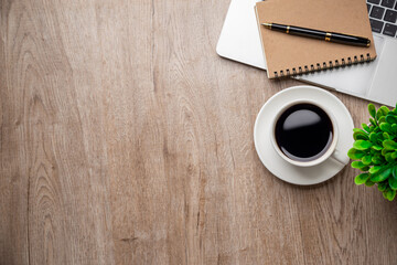 Flat lay, top view office table desk. Workspace with, laptop,office supplies, pencil, green leaf, and coffee cup on wood background.