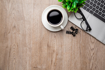 Flat lay, top view office table desk. Workspace with, laptop,office supplies, pencil, green leaf, and coffee cup on wood background.