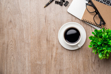 Flat lay, top view office table desk. Workspace with, laptop,office supplies, pencil, green leaf, and coffee cup on wood background.