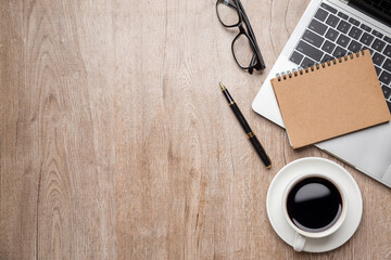 Flat lay, top view office table desk. Workspace with, laptop,office supplies, pencil, green leaf, and coffee cup on wood background.