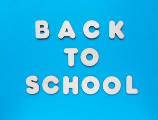 Inscription BACK TO SCHOOL made from wooden letters on blue background. The concept of the importance of education.