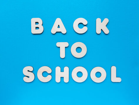 Inscription BACK TO SCHOOL made from wooden letters on blue background. The concept of the importance of education.