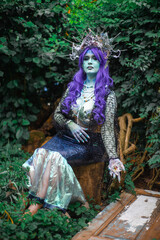 Fototapeta na wymiar fabulous dark mermaid with blue skin in the forest close up
