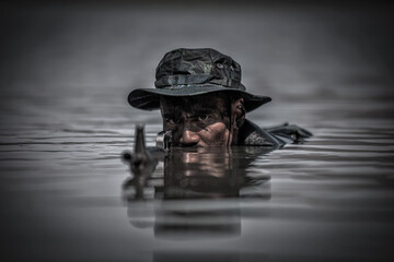 Soldiers with gun is hiding in the river. War, soldier army, gun and hostage rescue concept. - obrazy, fototapety, plakaty