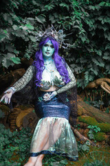 fabulous dark mermaid with blue skin in the forest close up