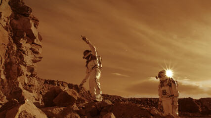 Astronauts climbing rocks and looking away on Mars