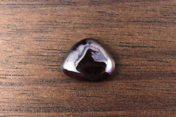 Garnet jewel stone texture on brown varnished wood background. Macro closeup.