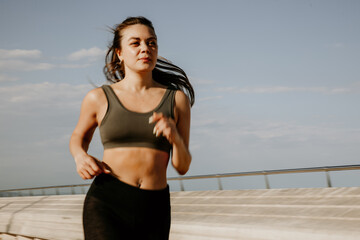 Female runner doing workout close to the beach. Sport and lifestyle concept.