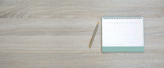 The top view desk and blank calendar with a pen and office equipment for working area copy space...