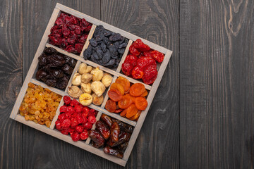 Dried fruits on a dark background top view. Dried dates, cranberries, apricots, dark and golden...