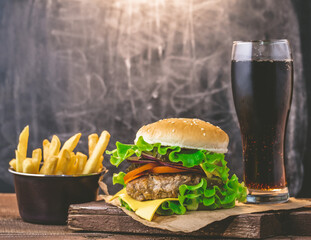 Burger with meat cutlet and fresh drink on a wooden background. Junk food concept.
