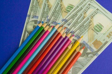 multicolored pencils on souvenir dollar bills. items lie on a blue background
