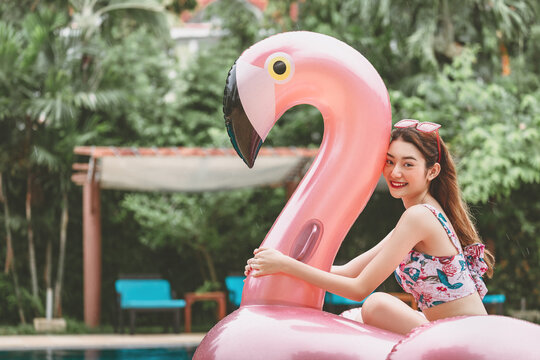 Happy summer asian bikini woman relax with pool float in resort Thailand
