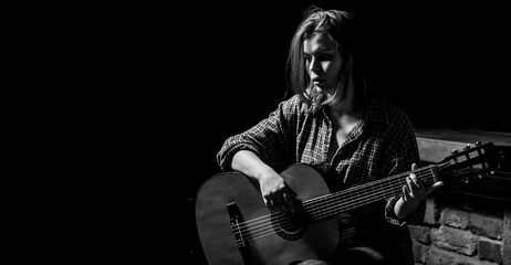 Woman playing guitar, holding an acoustic guitar in his hands. Music concept. Girl guitarist plays