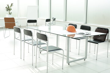 Flipchart construction helmet chairs briefcase glass table in office space