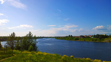 Obraz premium Blue sky over Velikaya River, Pskov, Russia. Beauty in nature. Landscape. Clear calm water. Green grass shore. Ecology concept. Environment conservation. Rural scene. Warm sunny summer day.