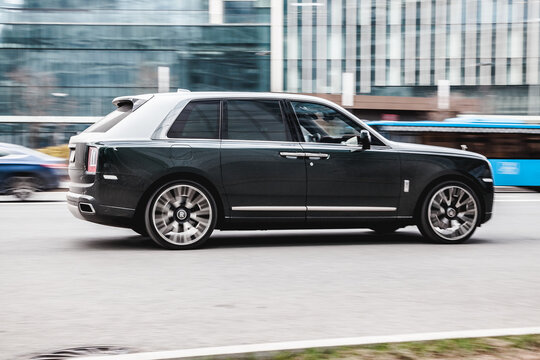 Fast moving Rolls-Royce Cullinan on the city road. Premium black SUV auto in fast motion with blurred background.