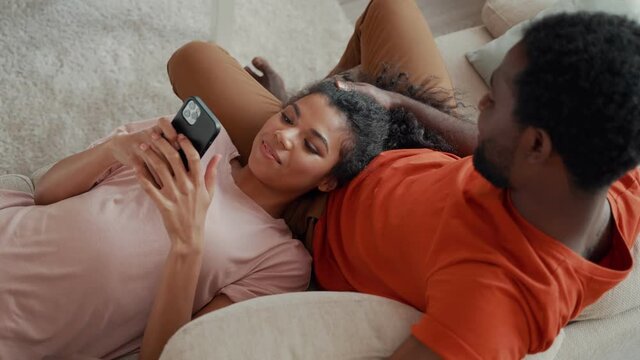 Top view of young African woman using smart phone with her boyfriend