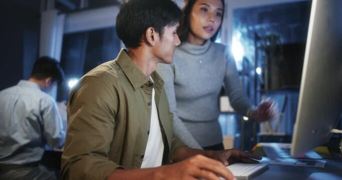Young Asian business man and woman work late night together on desktop computer with team in home office. Project brainstorm meeting, Small business startup, coworker cooperate teamwork concept