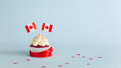 Cupcake with Canadian flags decorated with ribbon on blue background. Canada day celebration.