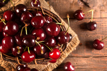 Organic red cherries in the wooden bowl on the rustic background with linen surface, retro style. Fresh berries for juices, smoothies, cakes, jam, marmalade. 