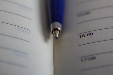 A blue automatic pen sits on the pages of an open notebook.