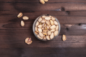 Fototapeta na wymiar Pistachios in a bowl on a wooden table. Salted pistachios for beer. View from above