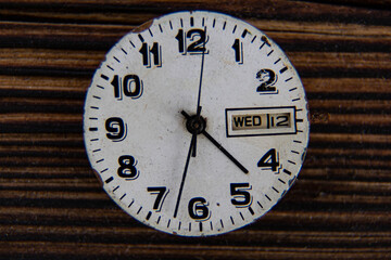The clock face of a vintage watch on a wooden table.