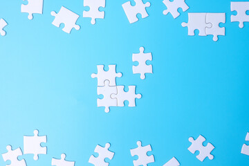 Group of white puzzle jigsaw pieces on blue background. Concept of solutions, mission, success, goals, cooperation, partnership, strategy and puzzle day