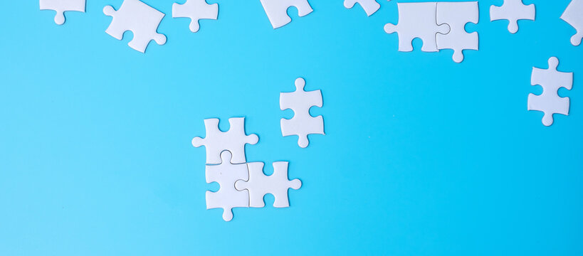 Group of white puzzle jigsaw pieces on blue background. Concept of solutions, mission, success, goals, cooperation, partnership, strategy and puzzle day