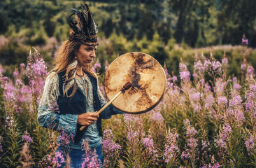 beautiful shamanic girl playing on shaman frame drum in the nature.