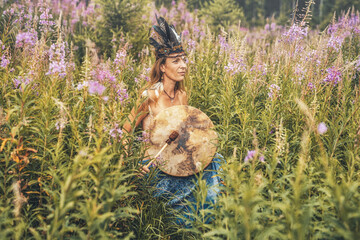 beautiful shamanic girl playing on shaman frame drum in the nature.