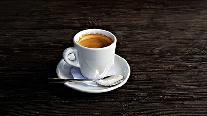 White cup with morning aromatic and delicious coffee on a black table