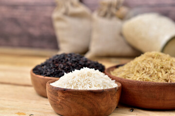organic white brown and black rice in a wooden bowls