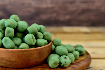 wasabi coated nuts with a wooden background
