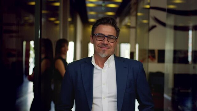 Business portrait - happy confident successful businessman in corporate office. Colleagues at workplace celebrating success.