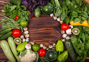 High angle of wooden cutting board surrounded by fresh herbs and assortment of raw vegetables on rustic wood table. Empty vintage frame. Ripe vegetables. Frame of assorted fresh vegetables. Still Life