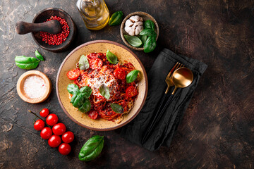 Italian pasta with tomato sauce, tomatoes, cheese and basil on a dark background top view
