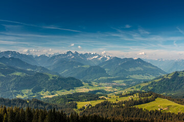 Fototapeta premium Panoramic landscape view of the Swiss Alpes,with blue sky in the background, shot in La Berra, Gruyère, Switzerland