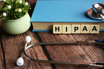 Wooden block written with HIPAA ( Health Insurance Portability and Accountability Act ) inscription with stethoscope, magnify glasses and flower.