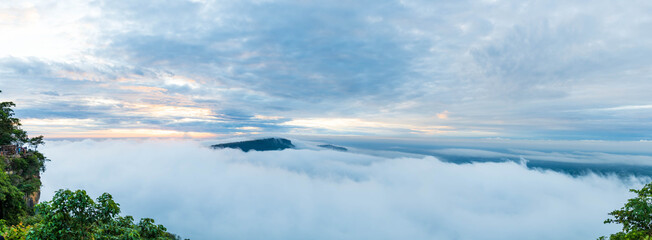 The atmosphere of the clouds has a beautiful orange-yellow glow from the sun. Above the white mist...