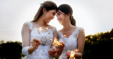 Portrait Of Asian Lesbian Couple With Wedding Dress Burning Bengal Light Fireworks.