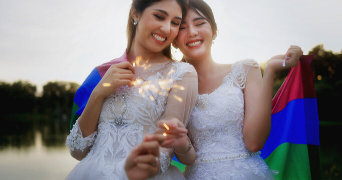 Portrait Of Asian Lesbian Couple With Wedding Dress Burning Bengal Light Fireworks.