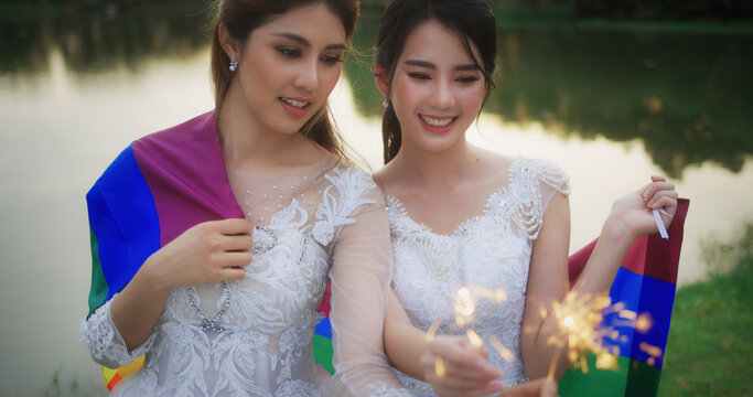 Portrait Of Asian Lesbian Couple With Wedding Dress Burning Bengal Light Fireworks.