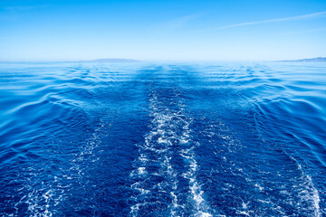 Aegean sea. Boat white wake, blue sea and sky background, view from the boat